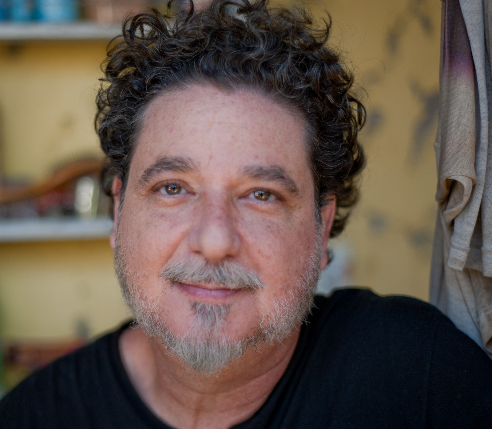 Kaio Carmona em retrato, com uma estante ao fundo.